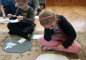 Dziewczynka rozwiązuje rebus, chłopiec układa puzzle.