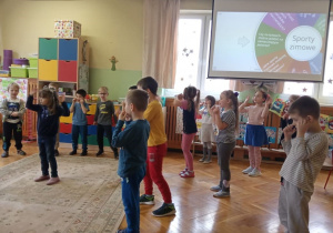 Dzieci śpiewają i ilustrują ruchem tekst.