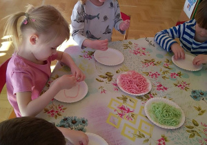 Dziecko układa obrazek z kolorowego makaronu