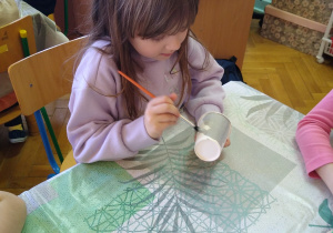 Dziewczynka maluje papierowy kubek na szaro