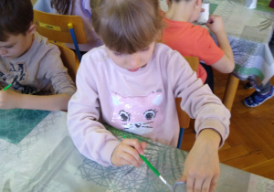 Dziewczynka maluje papierowy kubek na szaro
