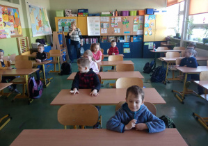 Dzieci siedzą w szkolnych ławkach