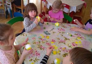 Dzieci oklejają bibuła styropianowe jajka