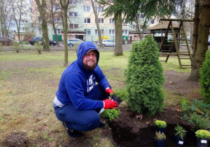 Tata Honoratki sadzi rośliny w ogrodzie przedszkolnym