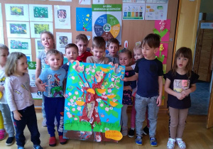 Dzieci pozują z plakatem przedstawiającym drzewo