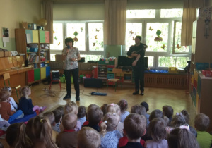 Wykonawcy prezentują dzieciom instrumenty strunowe szarpane.