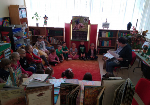 Dzieci słuchają czytanej przez panią bibliotekarkę książki