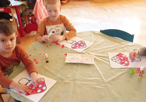 dzieci wyklejają papierem kolorowym muchomora