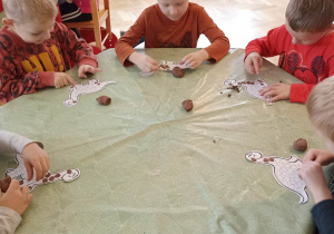 dzieci wyklejają plasteliną sylwetę dinozaura