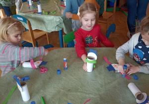 dzieci oklejają papierem kolorowym rolkę