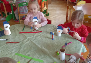 dzieci oklejają papierem kolorowym rolkę