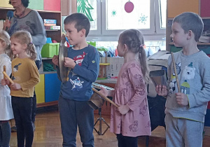 dzieci stoją i trzymają instrumenty