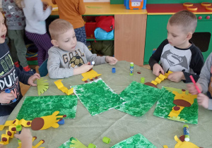 dzieci przy stole robią z papieru kolorowego żyrafę