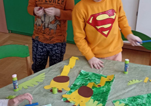 dzieci przy stole robią z papieru kolorowego żyrafę