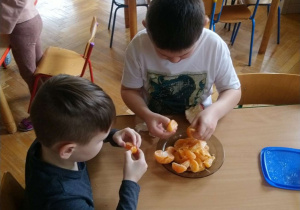 Chłopcy obierają mandarynki