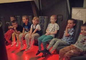 dzieci siedzą w planetarium