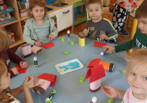 dzieci wyklejają domki z rolek i papieru kolorowego
