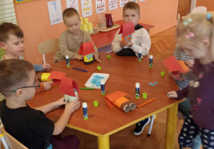 dzieci wyklejają domki z rolek i papieru kolorowego