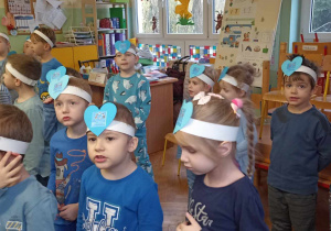dzieci stoją , na głowach mają opaski z niebieskim serduszkiem