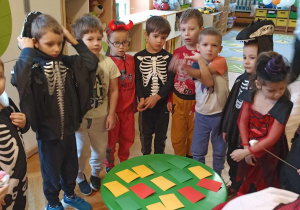 dzieci stoją przy stoliku na którym leżą kolorowe karteczki