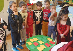 dzieci stoją przy stoliku na którym leżą kolorowe karteczki