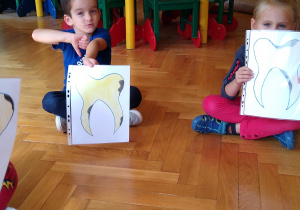 Dzieci trzymają kartki z narysowanym zębem