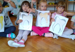 Dzieci trzymają kartki z narysowanym zębem