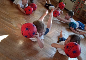 dzieci leżą i podnoszą piłkę