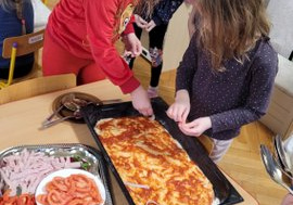 Dzieci układają skłądniki na pizzy