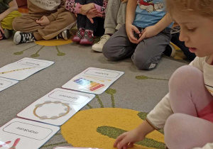 dzieci siedzą na dywanie i układają ilustracje instrumentów
