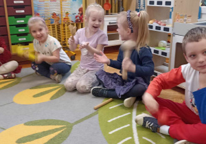 dzieci siedzą na dywanie z instrumentami perkusyjnymi