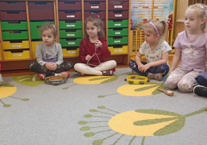 dzieci siedzą na dywanie z instrumentami perkusyjnymi