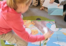 Dzieci układają duże puzzle z dinozaurami