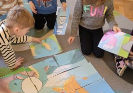 Dzieci układają duże puzzle z dinozaurami