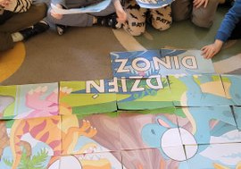 Dzieci układają duże puzzle z dinozaurami