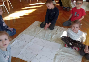 dzieci siedzą przy dużym rysunku