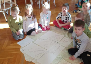 dzieci siedzą przy dużym rysunku