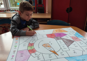 Chłopiec koloruje matematyczną kolorowankę