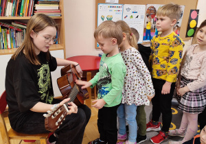 Dzieci próbują zagrać na gitarze.