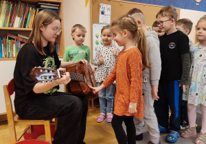 Dzieci próbują zagrać na gitarze.