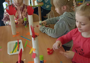 dzieci doklejają elementy z papieru kolorowego do rolki