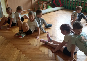 dzieci siedzą na podłodze i ćwiczą