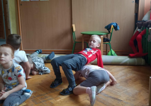 dzieci siedzą na podłodze i ćwiczą