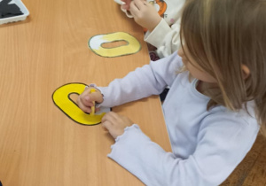 dzieci kolorują literę o i doklejają elementy
