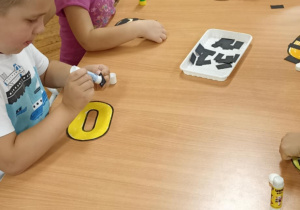 dzieci kolorują literę o i doklejają elementy
