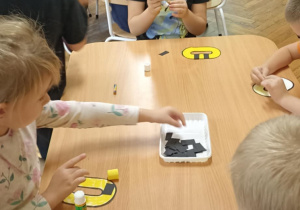 dzieci kolorują literę o i doklejają elementy