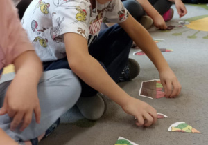 dzieci układają puzzle na dywanie