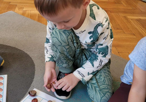 Dzieci układają wzory z kasztanów w lustrzanym odbiciu