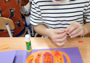 dzieci wyklejają bibułą sylwetę dyni