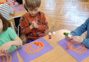 dzieci wyklejają bibułą sylwetę dyni